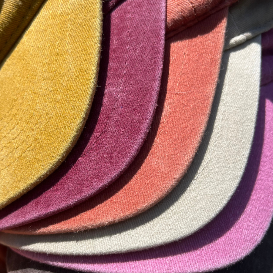 Stack of colorful fabric swatches in various shades, showcasing all of our hand-embroidered bow hats
