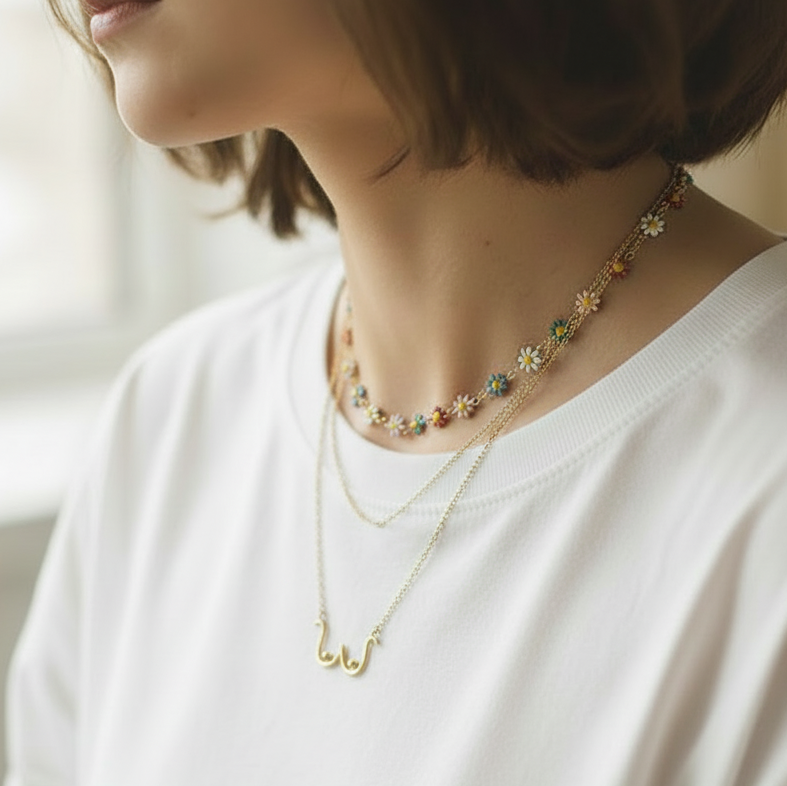 Young woman wearing a delicate gold necklace with floral elements on a blurred background