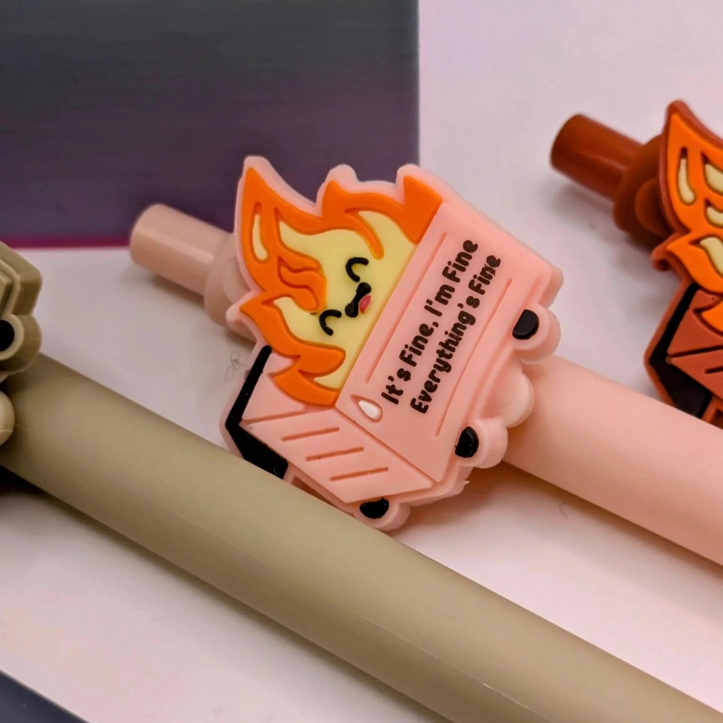 Pen with a dumpster on fire illustration on top that says " it's fine, I'm fine, everything's fine"