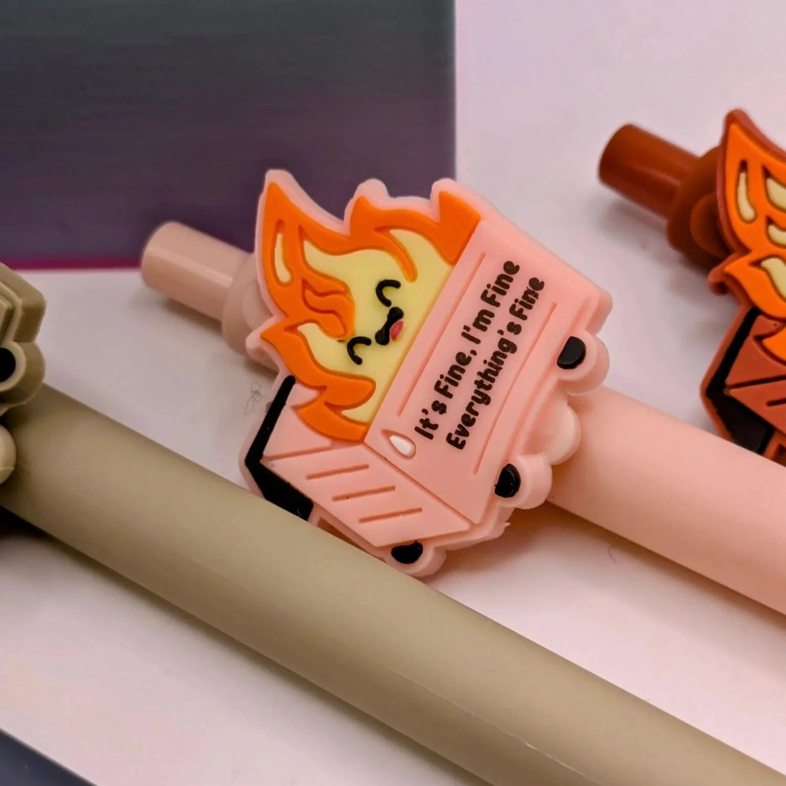 Pen with a dumpster on fire illustration on top that says " it's fine, I'm fine, everything's fine"